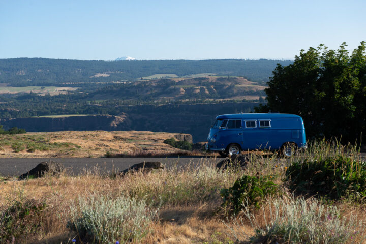 Small camper on a overlook with a mountain peak in background during clear and sunny day.